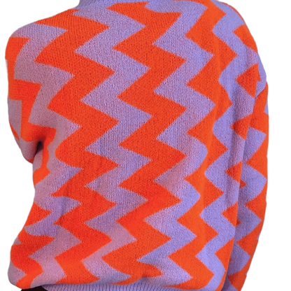 Close-up of a sweater with orange and purple zigzag pattern on a gray background